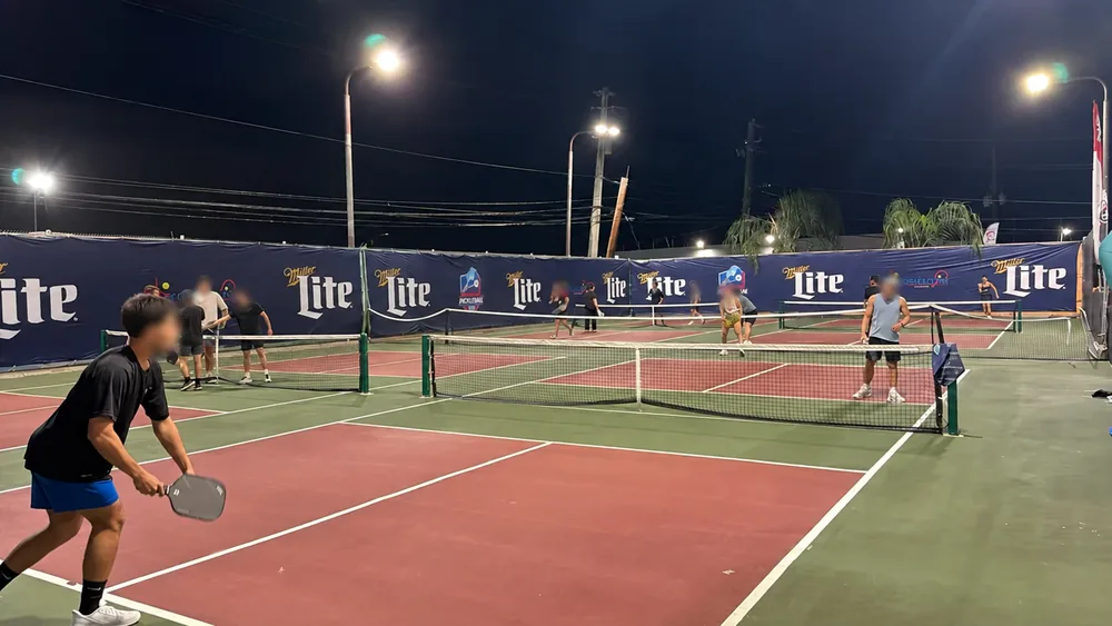 Vista nocturna amplia de lonas en una cancha de pickleball, con datos privados ocultos
